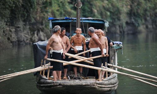 Old boatmen perform work songs for tourists on Youshui River in Baojing, China's Hunan